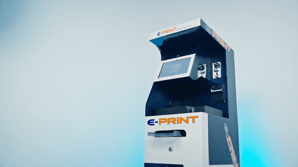 The E-Print vending kiosk with its touchscreen, coin and bill acceptors, and print tray
